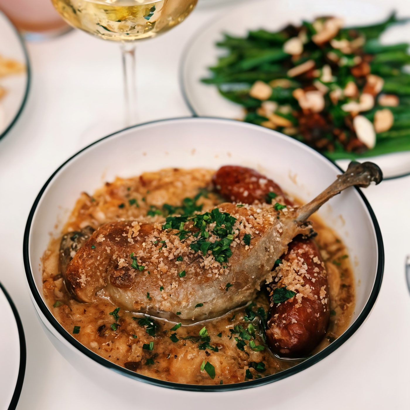 Duck confit with sausage, beans and a glass of white wine